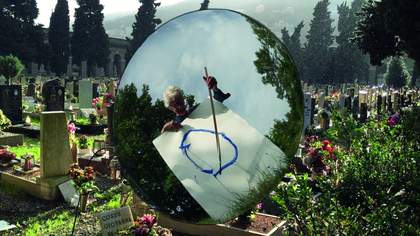 man standing in graveyard painting a circle