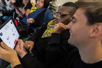 A teacher and student are exploring an interactive making tool on a tablet device in the classroom