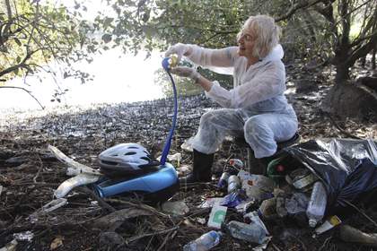 Bonita Ely sits among plastic rubbish in a white boiler suit