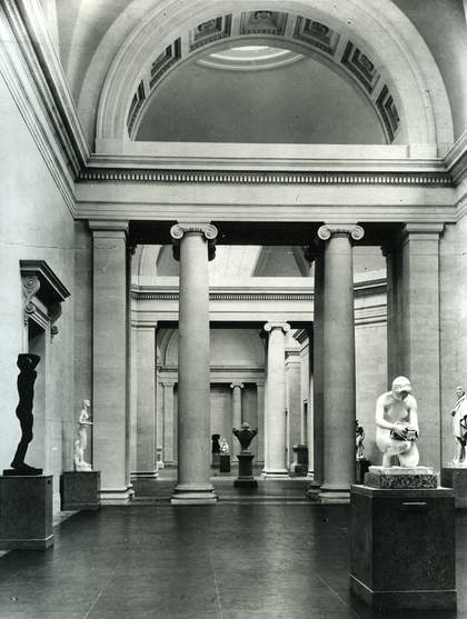 Black and white photo of the Duveen Gallery at the Tate Britain. There are a few sculptures and a neo-classical style room.