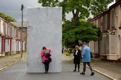 Photograph of some people looking at a large stone sculpture