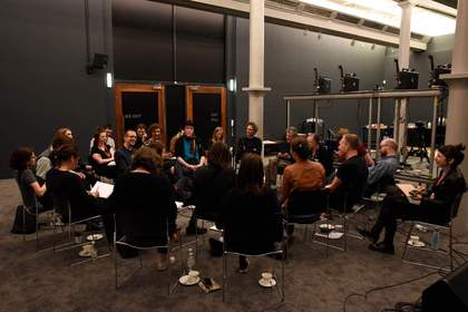 People sitting on chairs in a circle in a studio space