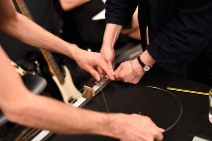 Close up of hands restringing an instrument