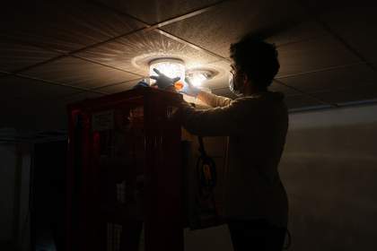 An individual with gloved hands attaching a glass lamp to the ceiling