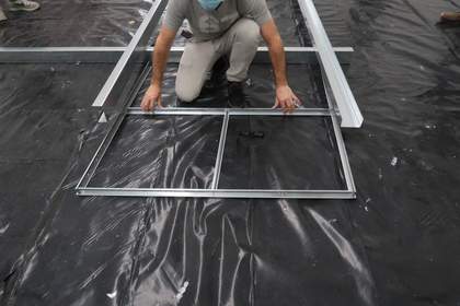 An individual sliding a section of a metal grid into a larger metal structure