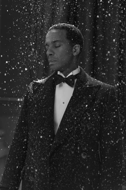 A black and white photograph of a man wearing a tuxedo in the snow