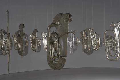 Squashed brass band musical instruments hung from the ceiling in a circle