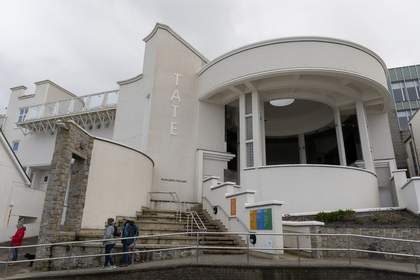The front of the Tate St Ives gallery building. The building is large, white and round and there are steps leading up to it.
