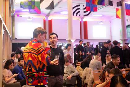 Two people drinking in the Tate Liverpool cafe during an event with lots of other visitors eating and drinking in the background