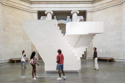 People looking at an artwork that is a large white cast of a staircase