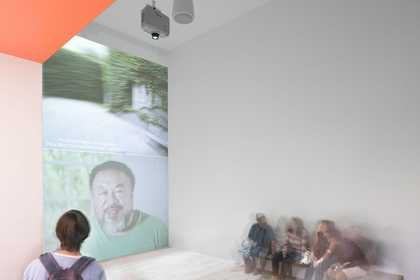 Man looks onto a wall where Ai Weiwei's face is being projected