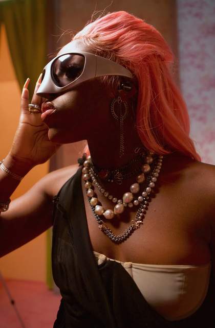 A woman with large sunglasses peers away from the camera