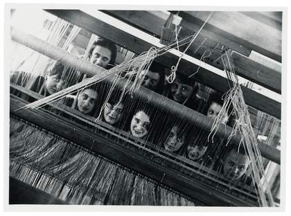 A group of Bauhaus weavers looking through the loom in to the camera