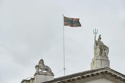 A black, green and red version of the union jack flag flying above Tate Britain