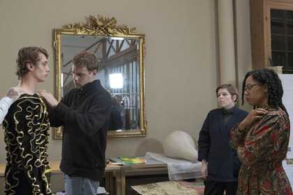 people tailor a costume in front of a mirror