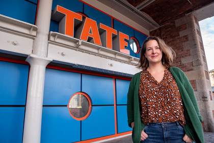 Emily Speed poses in front of Tate Liverpool's sign.
