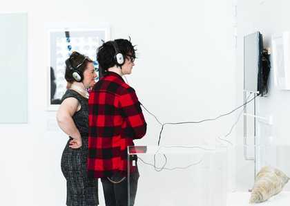 Visitors looking at art and listening to audio in a gallery