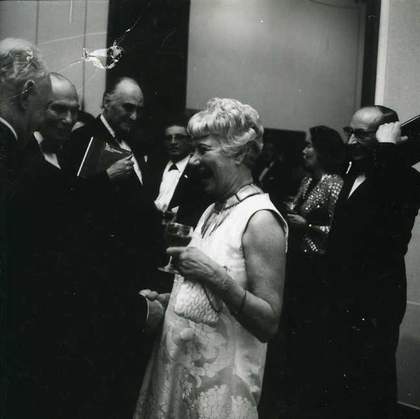 Fig.2 ​​​​​​​Peggy Guggenheim and Norman Reid surrounded by guests at the opening of The Peggy Guggenheim Collection, Tate Gallery, London, 1 January 1965