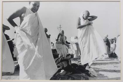 Two figures wrap robes around their bodies in an outdoor setting.