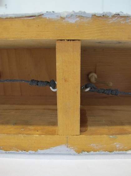 A close-up view showing two horizontal pieces of wood connected by a vertical one, with a vertical pencil line drawn above the central point of the vertical piece of wood.