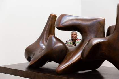 Woman looking through a gap in a large abstract sculpture