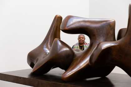 Woman looking through a gap in a large abstract sculpture