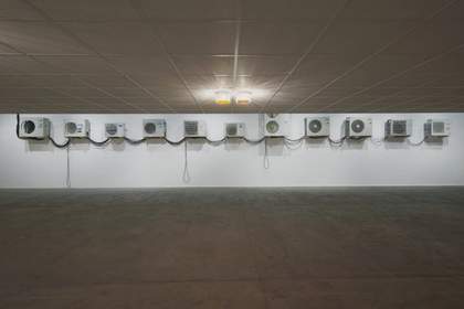 a series of air conditioning units are arranged in a line in a gallery space