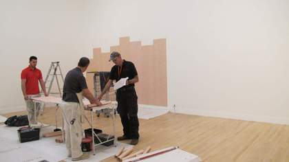 Three people installing an artwork in a gallery