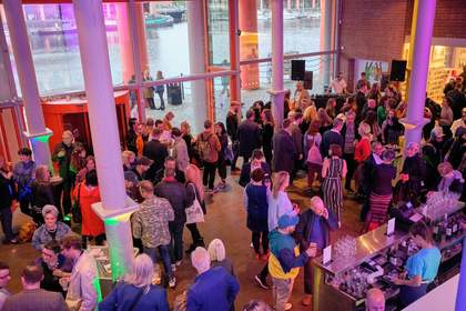 A photograph looking down into the foyer of Tate Liverpool full of people chatting.