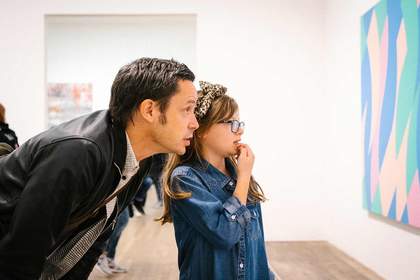 girl and father looking at art