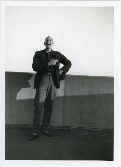 Len Lye stands in front of a low wall