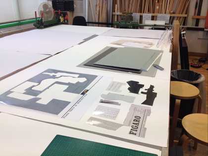 A paper collage replicating the original Picasso under construction on a work table surrounded by paper and a cutting blade