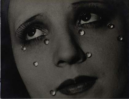 Black and white photograph of a close up portrait of a woman who has glass 'tears' on her face