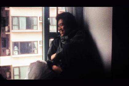 A person sits by a window smiles and looks out 