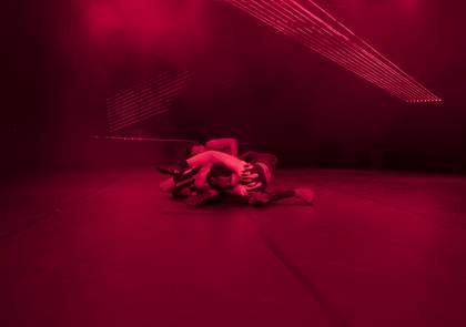 Human figures are seen on a floor intertwined with a hot pink filter on the room