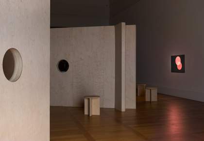 photograph of the exhibition. plywood structures small stools and a film projected onto the wall