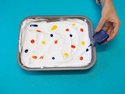 dropping ink into shaving foam, a pattern of dots across the surface in different colours 