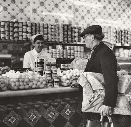 Scottie Wilson wearing his tweed cap while shopping at Sainsbury’s, 1964, photographed by Ida Kar