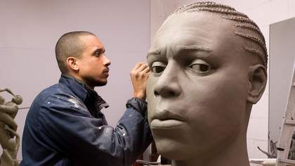 Thomas J Price carving a sculpture out of clay 