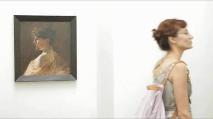 Still from video showing visitor looking at art